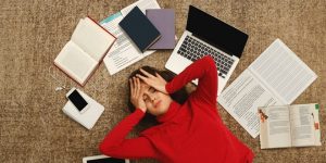 tired student girl lying on the floor with books and gadgets picture id932274694