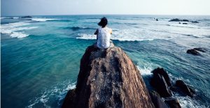 young woman sit on seaside rock cliff edge looking at the distance picture id1077587988