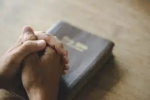 Christian life crisis prayer to god. Man Pray for god blessing to wishing have a better life. man hands praying to god with the bible. believe in goodness. Holding hands in prayer on a wooden table.